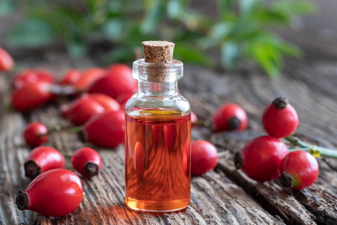 A bottle of rosehip seed oil with fresh rosehips